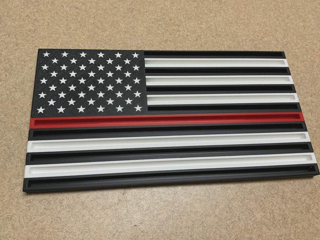 Thin Line Flag Challenge Coin Display with black, white and red stripes and white stars, on a tan surface