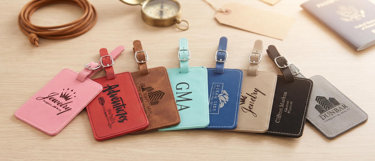 Engraved leatherette luggage tags fanned out with passport and compass